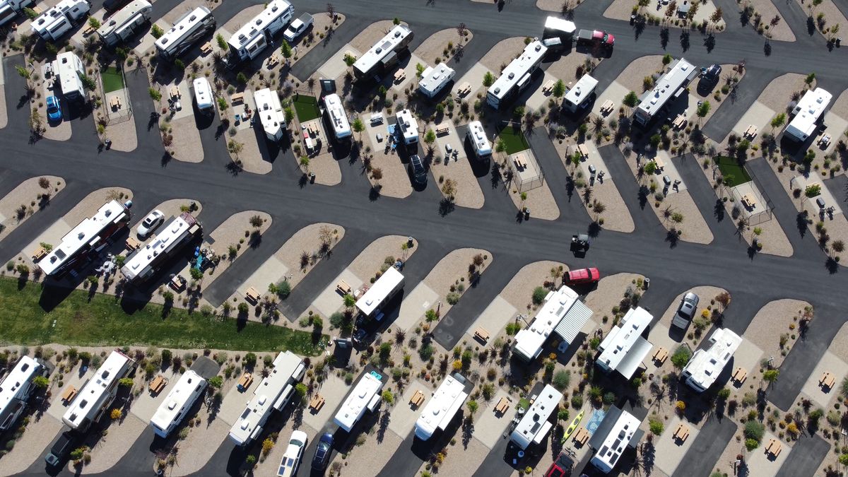 Aerial view of motorhomes and travel trailers parked in rows of desert-landscaped sites at a sunny RV resort