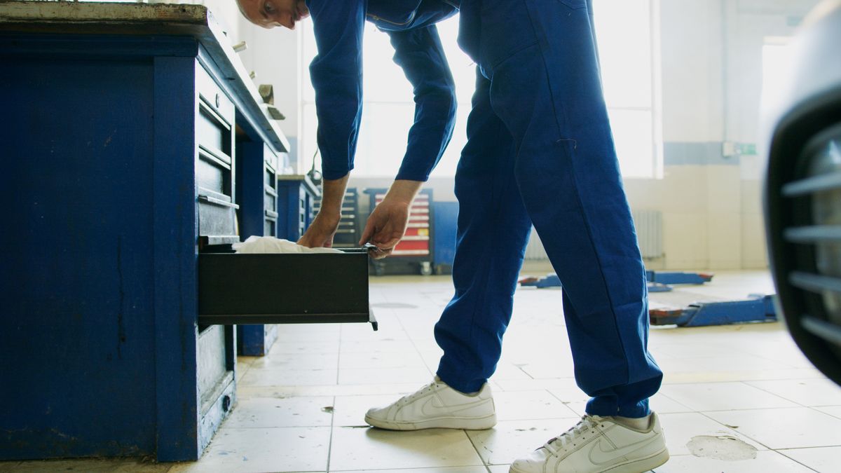 RV technician in work coveralls opening a tool chest drawer in a repair workshop
